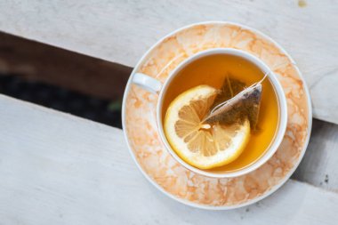 Bir fincan taze, siyah çay ve limon dilimi.