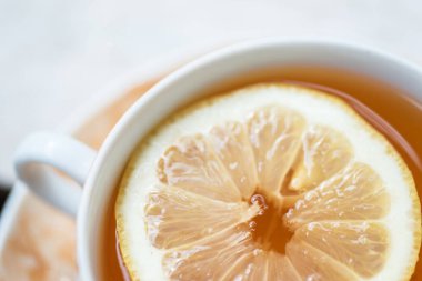 Bir fincan taze, siyah çay ve limon dilimi.