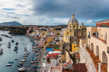 Güneşli yaz gününde güzel Procida manzarası. Marina Corricella 'da renkli evler, kafeler ve restoranlar, balıkçı tekneleri ve yatlar,