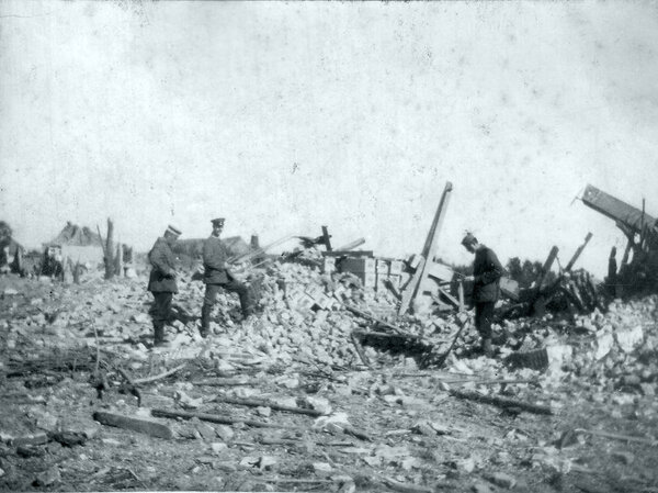 Three german soldiers walking through ruins of village