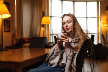 Muhteşem mutlu kadın bir kafe arka plan kahve içer. Rahat ekose kaplı. Bulanık kafe arka plan.