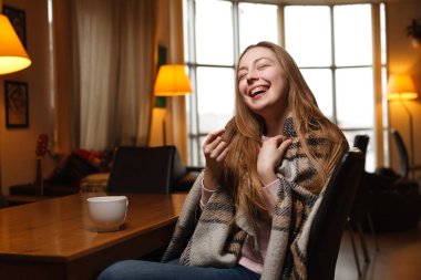Muhteşem mutlu kadın bir kafe arka plan kahve içer. Rahat ekose kaplı. Bulanık kafe arka plan.