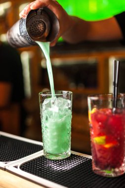 Uzman barmen mavi, turkuaz ve kırmızı kokteyl yapmak, yakın çekim çubuk