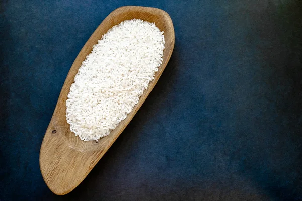 Рис в деревянной тарелке, которая помещается на темно-синем фоне поверхности — стоковое фото