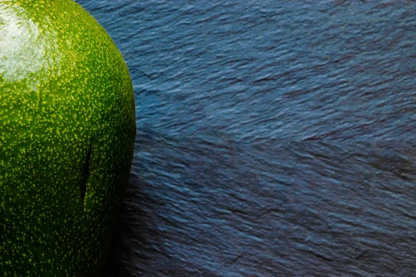 Fruta de abacate verde completa na superfície de fundo de pedra preta — Fotografia de Stock