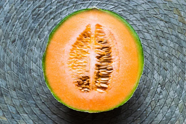 Metade do Hami Melon Fruit na superfície de fundo do tapete de palha verde — Fotografia de Stock