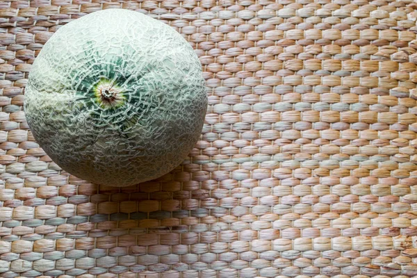 Hami Melon Fruit na superfície de fundo do tapete de palha marrom — Fotografia de Stock