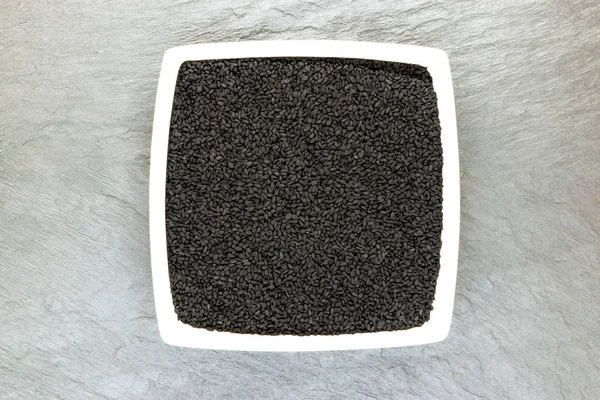空き領域のある白地石表面に白い板の (ニゲラ Sativa またはカロンジ) ブラック クミン種子 — ストック写真