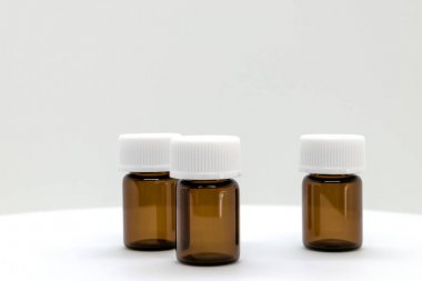 Üç kahverengi örnek şişe boş alan beyaz zemin üzerine beyaz kapaklar ile