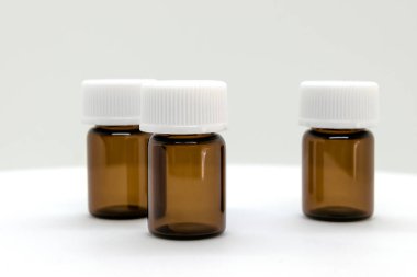 Üç kahverengi örnek şişe boş alan beyaz zemin üzerine beyaz kapaklar ile