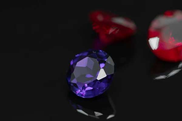 Batu permata ungu dan batu rubi merah pada permukaan reflektif hitam — Stok Foto