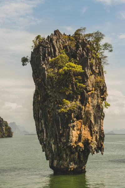 James Bond Adası, mavi gökyüzünün önünde, beyaz bulutlar, yeşil su ve görünen dağlarla Phang Nga Körfezi Tayland 'da.
