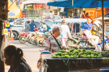 Tayland Bangkok 4 MAR 2020 Sokak yaşam konsepti. Tren pazarındaki yaşlı kadın sabah taze mango meyveleri alıyor. Klasik ton filtresi renk biçimi