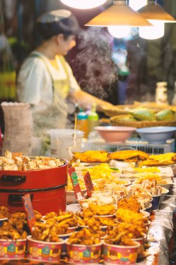 Tayland Krabi 5 MAR 2020 sokak yemeği, seyahat ve yaşam tarzı konsepti. Yerel marketteki yiyecek satıcısı tezgahın yanında duruyor ve kaynar su buharı ile kaplı. Fiyat etiketleri kamera odaklı