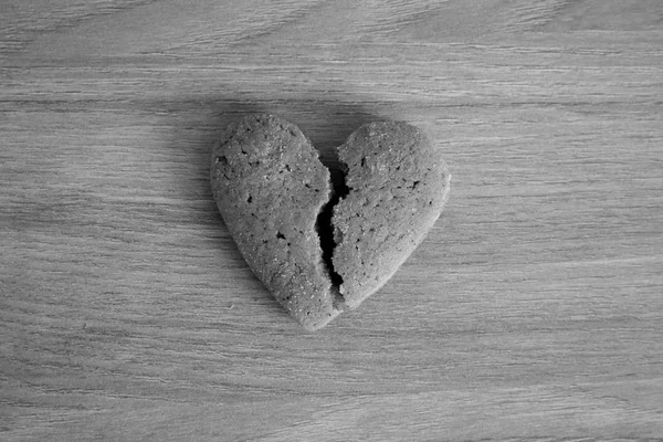 Single shortbread broken heart black and white. Unhappy love concept. Love symbol. Monochrome. Heart cookie. Loneliness background. Romantic food. Valentines day.