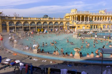 Budapeşte, Macaristan - 02/19/2018: termal hamam Szchenyi rahatlatıcı ile açık hava güneşli günde insanlar. Ünlü Macar spa Hamam. Sakin ol ve eğlence kavramı. Sıcak termal yüzme havuzu üzerinde buhar.