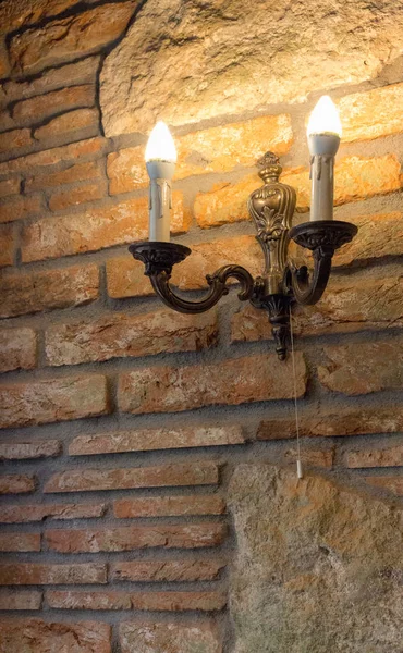 古代の建物のレンガの壁の上にランプとローソク足 中世風の内装 石とレンガの古い家 旅行と建築のコンセプトです ヴィンテージとグランジの装飾 キャンドルと燭台 — ストック写真