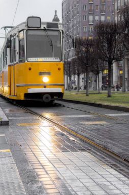 Gri şehir sokak üzerinde eski sarı tramvay. Kentsel vintage tren. Ulaşım ve seyahat kavramı. Sarı lokomotif raylar üzerinde. Budapeşte, Macaristan, Avrupa'nın şehir tramvay. Budapeşte Simgesel Yapı ve ulaşım.