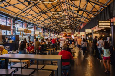 Porto, Portugal - 10/23/2018: Interior of food court in Porto. Crowd of tourists eating in cafes. Urban food court in Porto. Portuguese cuisine concept. Market hall with unknown people and cafe tables.  clipart