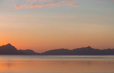 Filipinler, Palawan 'da günbatımının güzel arka planı. Ufukta adalar ve dağlarla denizde sakin bir gün batımı. Denizde akşam karanlığı. İyi akşamlar deniz manzarası. Yumuşak renklerde tropik bir göl. 