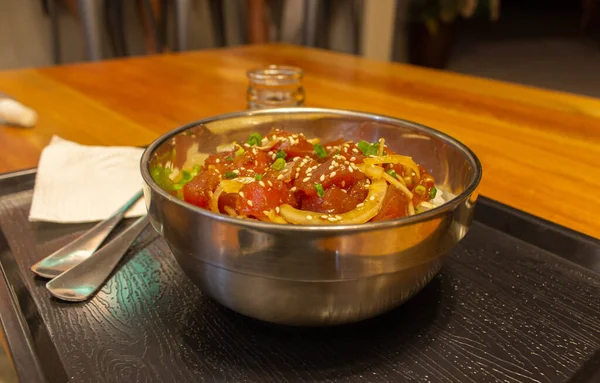 Traditional hawaiian meal called poke with fork, spoon and soy sause. Bowl of rice and raw chopped fish with onion. Asian cuisine. Raw salmon with rice. Healthy tropical food in restaurant. Seafood concept. Delicious poke bowl. — Stock Image Traditional Hawaiian Meal Called Poke Fork Spoon Soy Sause Bowl Stock Image