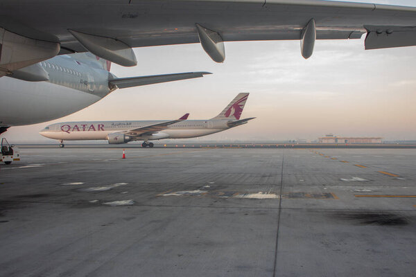 Doha, Qatar - 02/16/2020: airplane of "Qatar airways" at empty international airport. Jet of "Qatar airways" at sunset. Quaratine in airport. Empty runway of airport in Doha in evening haze. Pause in transportation industry. Air travel concept. 