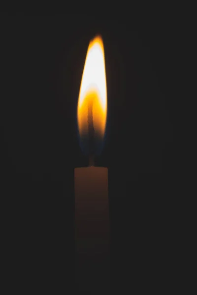Candle on black background soft toned. Candlelight in the dark. Hope concept. Glowing candle close up. Fire in the night. Grief and sorrow concept. Candle with unfocused flame.