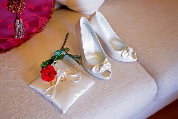 Skor av bruden och en kudde med ringar och röd ros — Stockfoto