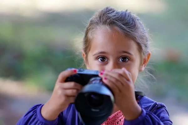 Красивая маленькая девочка с фотоаппаратом фотографирует — стоковое фото
