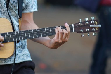 Bir müzisyen gitar çalar, ellerin detaylarını.