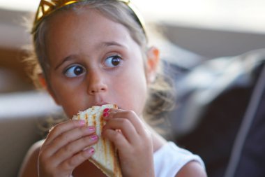 4 yaşındaki bir kız zevkle sandviç yer.