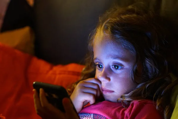 4 year old girl looks with interest at her cell phone — Stockfoto