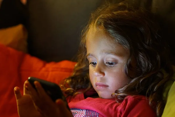 4 year old girl looks with interest at her cell phone — 스톡 사진