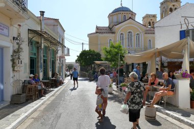 Çeşitli milletlerden turistler, Yunanistan 'ın Potamos kentindeki merkezde gezinerek rahatlıyorlar.
