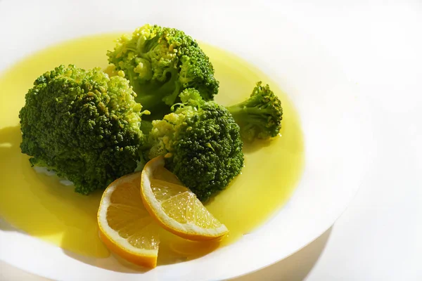Cooked broccoli on white plate with lemons