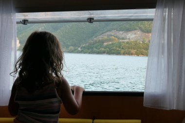 4,5 yaşındaki bir kız, pencereden Yunanistan 'daki Igoumenitsa Körfezi' nin manzarasına bakıyor