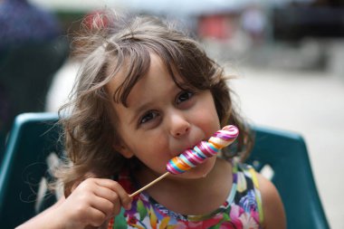 4 yaşındaki İtalyan kız bir tutam renkli şeker yiyor.