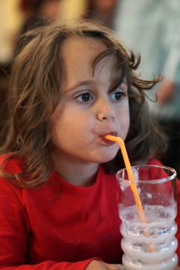 4 yaşındaki İtalyan kız içkisini pipetle içiyor.