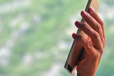 Pencerenin yanında akıllı telefon kullanan parmakların ayrıntıları
