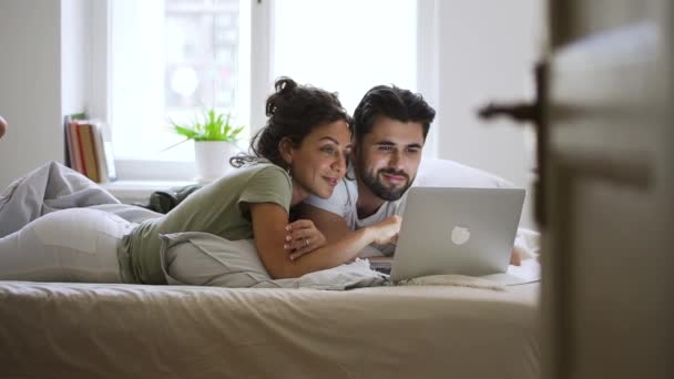 Beautiful American couple is lying on bed and using laptop in modern apartment spbd image