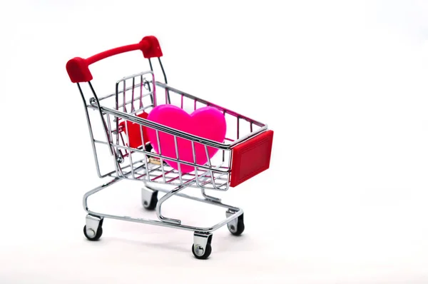 Beyaz arka plan üzerinde izole bir alışveriş sepeti içinde pembe kalp