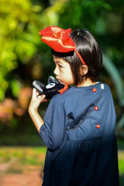 Surin, Tayland - 31 Ekim 2018: Kiki 'nin Teslimat Servisi' nden Kiki gibi giyinmiş bir kız, Studio Ghibli karakterleri ve Jiji 'nin ünlü kedi karakteri Cadılar Bayramı' nda.