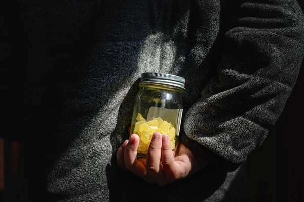 Kız şekeri arkasına saklar. Yetişkinlerin çok fazla yemenin sağlıksız olduğu uyarılarını görmezden gelerek yemeye devam etmek için..