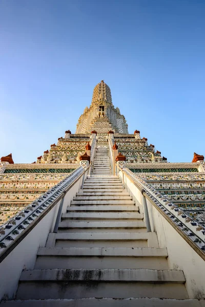 Wat Arun Ratchawararam tapınağının dikey görüntüsü, Tayland, Bangkok 'un önemli simgesi. Resmin ortasında birçok basamak var ve kulenin tepesine çok yüksek..