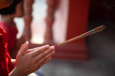 Elinde tütsü tutan kadın saygı duyduğu kutsal şeylerden kutsanmak için elleriyle yakıyor..