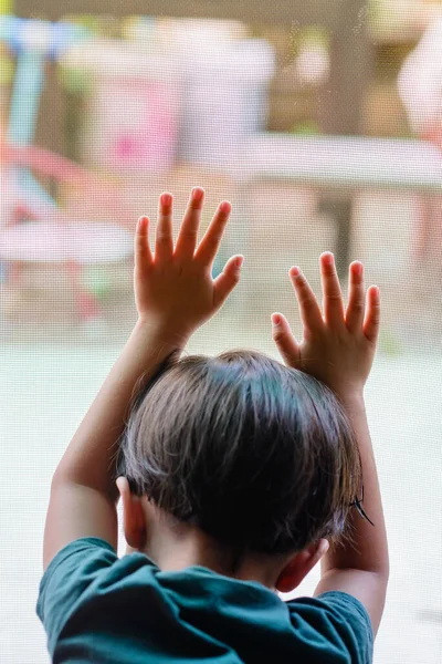 One boy placed both hands on a mosquito net. He wants to go play outside. But the situation outside of the epidemic Causing him to stay in the house for safety