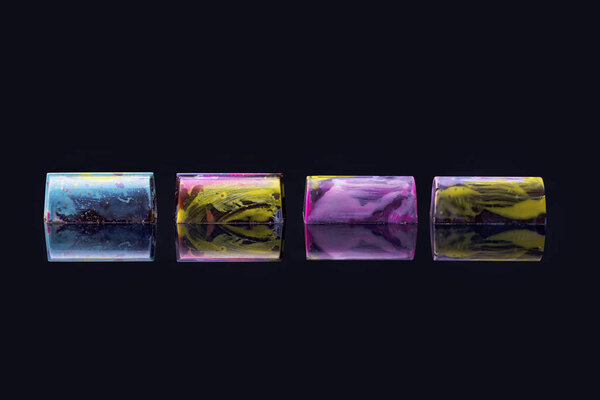 Colorful cakes with marble glaze on black background