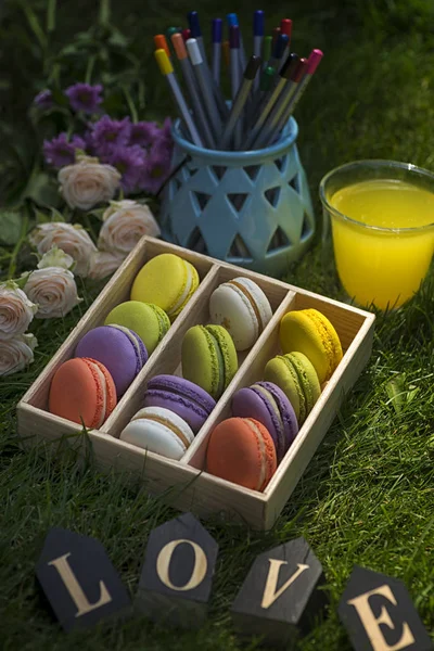 Kutu macarons çiçek ve ahşap harfler ile yeşil çimenlerin üzerinde