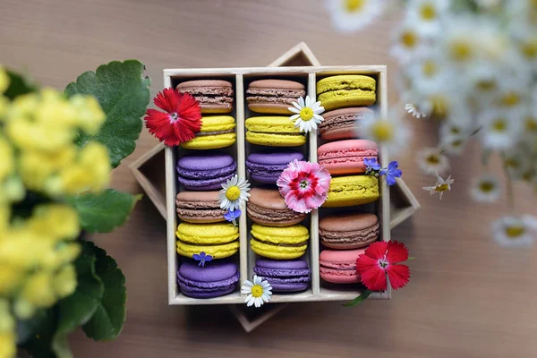 Renkli macarons taze çiçeklerle süslü kutu