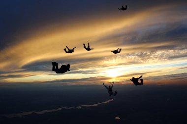 Gün batımı paraşütle atlama. Şaşırtıcı gökyüzü ve skydivers.